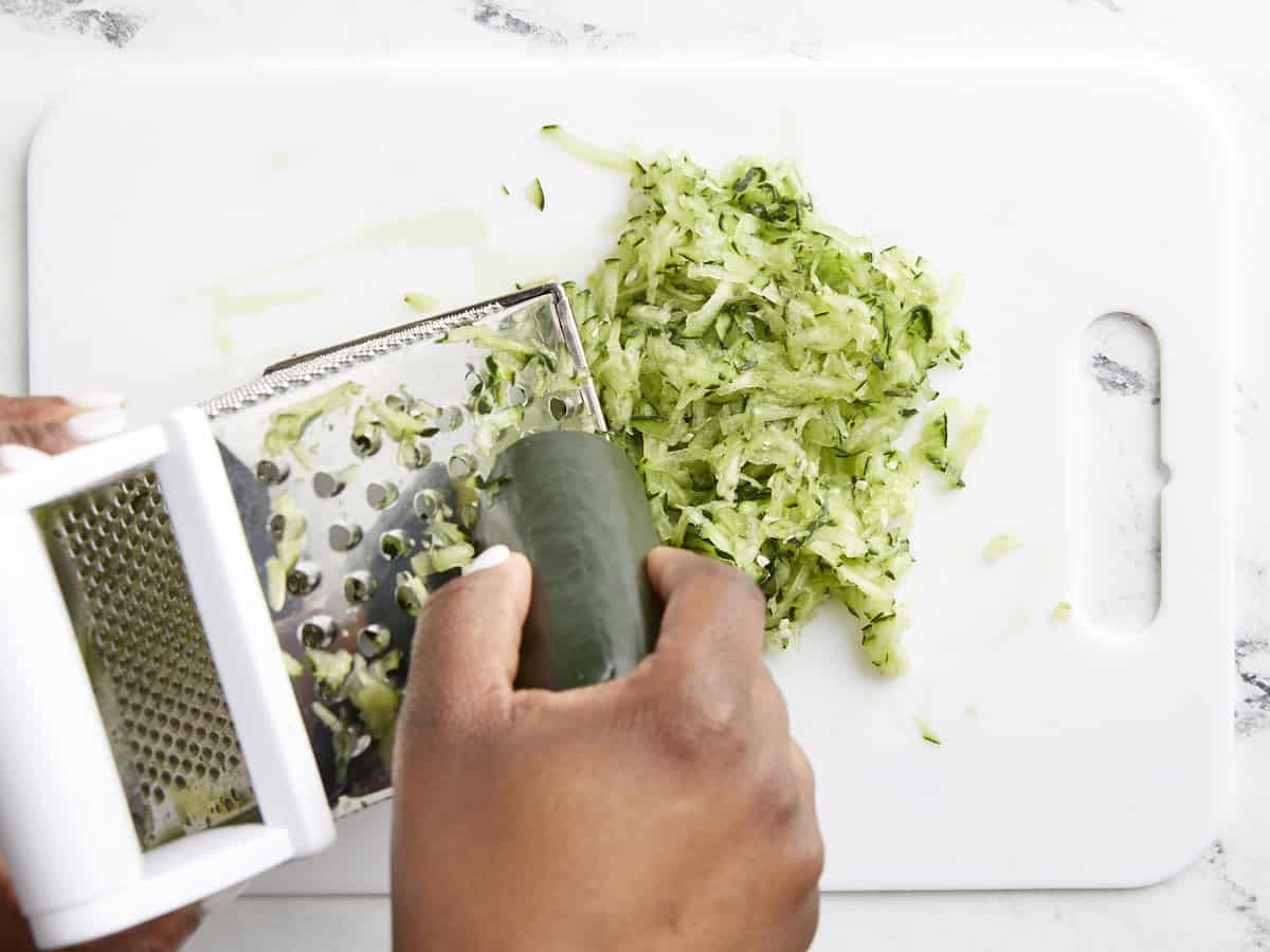 Cucumber being grated on a box grater.