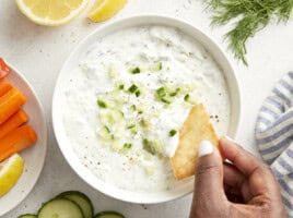 Overhead view of tzatziki sauce with a pita chip being dipped in the sauce.