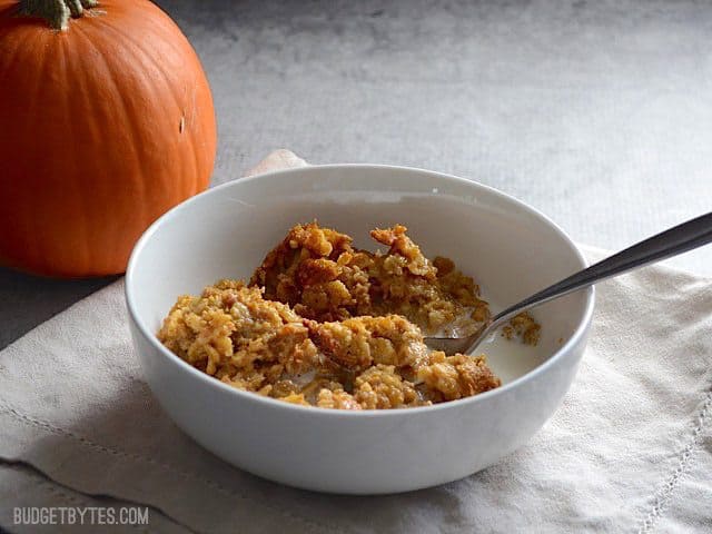 Vista lateral de un tazón de Harina de Avena para Pastel de Calabaza al horno con una calabaza en el fondo