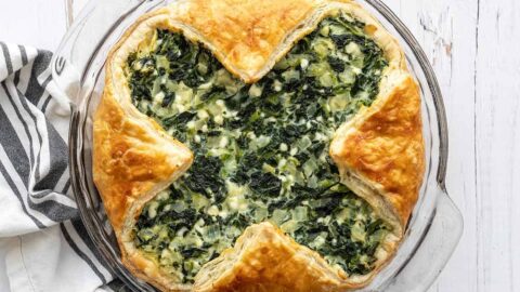 Overhead view of spinach pie in the glass pie dish on a wooden surface