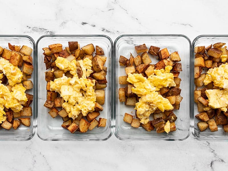 Add eggs to roasted potatoes in meal prep containers