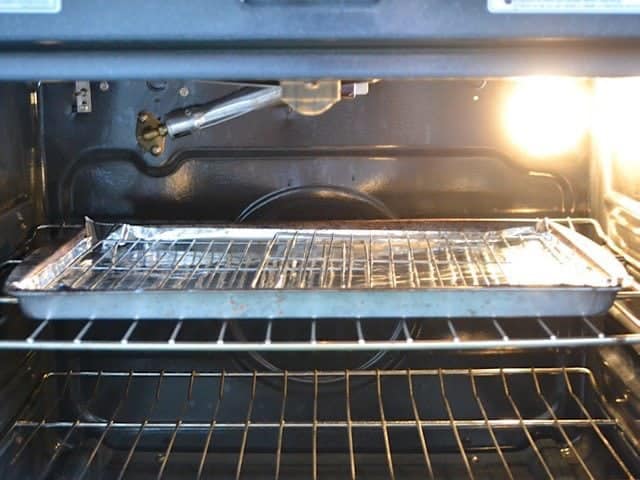 Sheet pan fitted with wire cooling racks in the oven close to the broiler