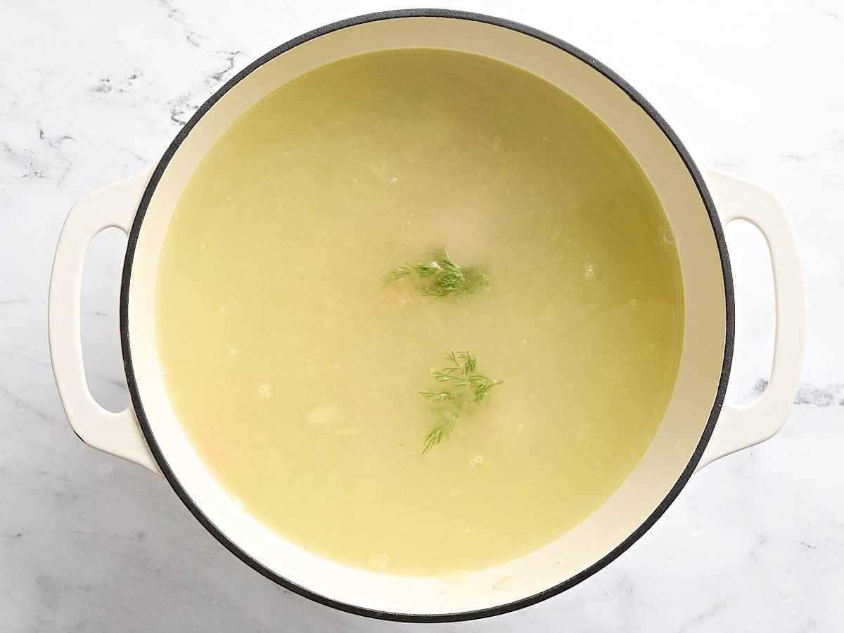 Fresh dill added to matzo ball soup in a sauce pot.