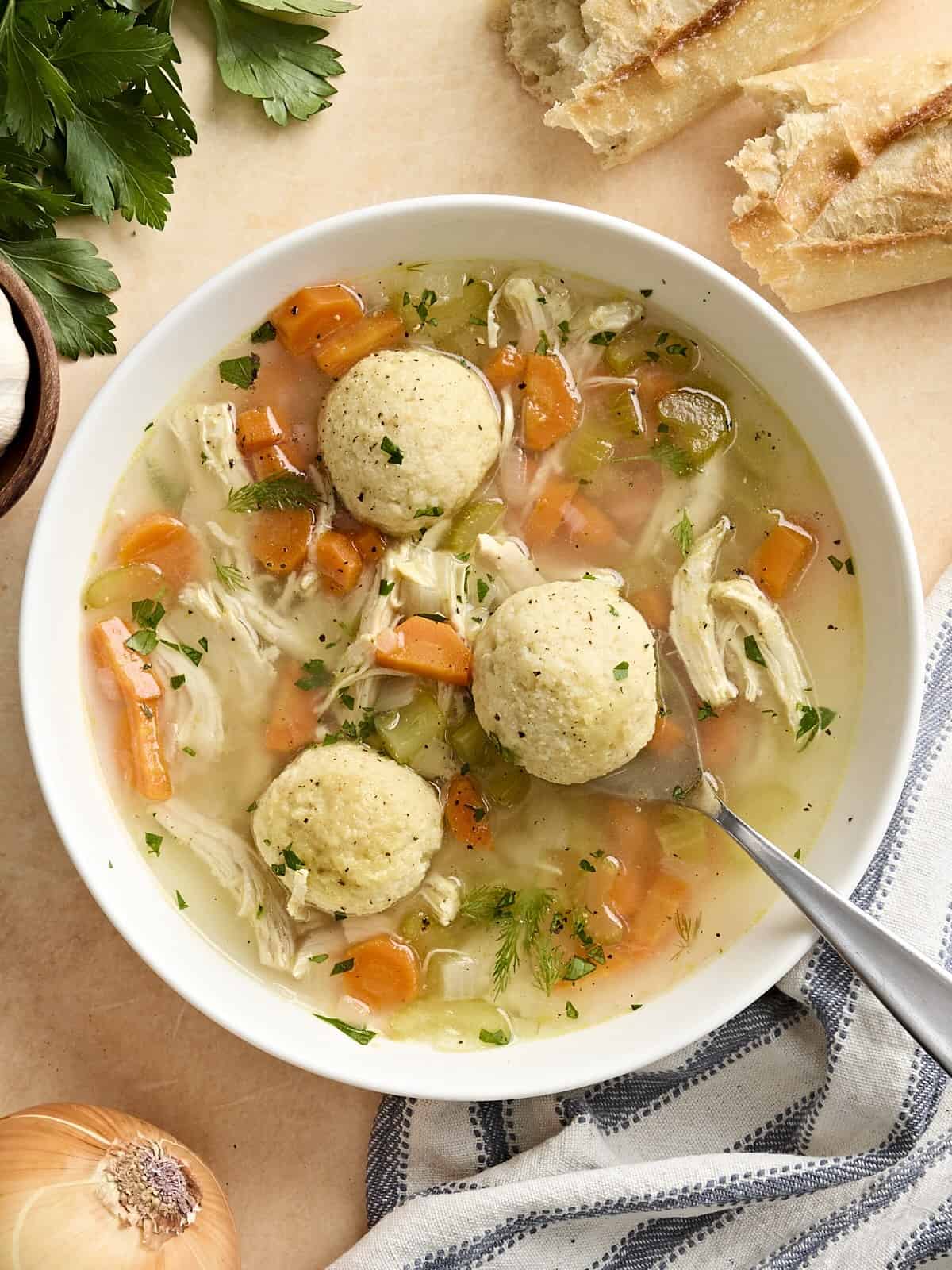 Overhead view of matzo ball soup in a bowl with a spoon.