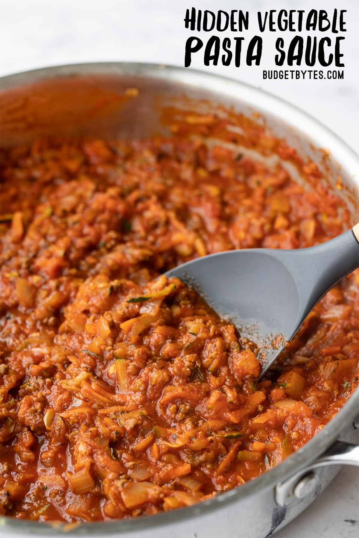 CLose up side view of pasta sauce in a skillet with a spatula, title text at the top