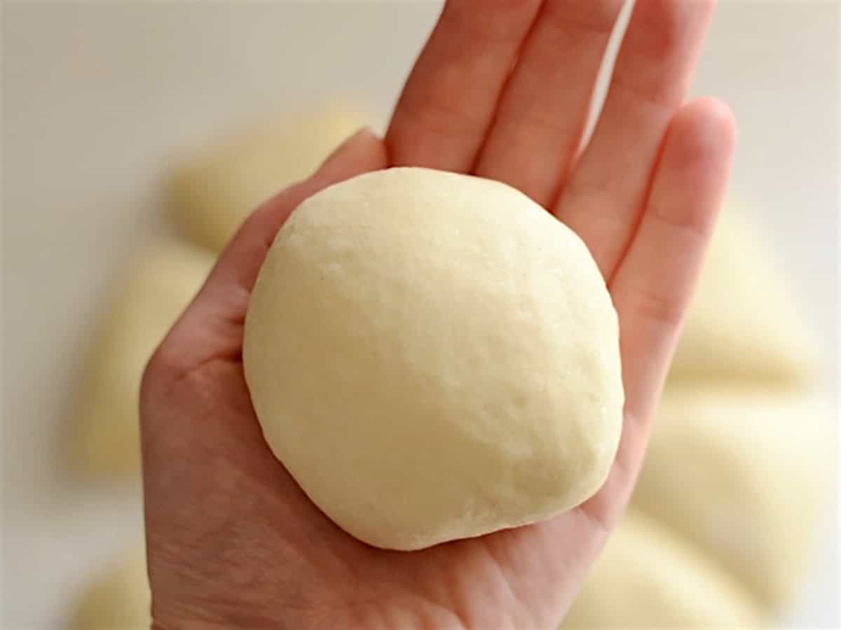 portioned dough shaped into a ball in the palm of a hand. 
