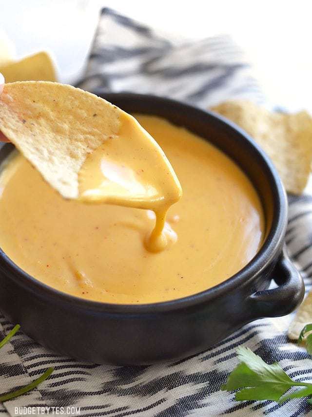 Chip dipping into thick and creamy 5 Minute Nacho Cheese Sauce