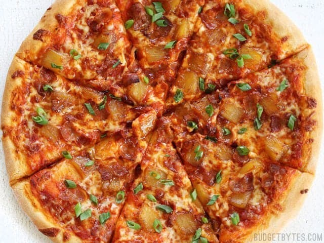 Overhead view of the sliced Bacon Pizza with Caramelized Pineapple and green onion