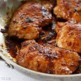 Close up side view of glazed pork chops in a skillet.