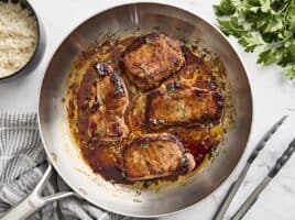 Overhead view of glazed pork chops in a skillet.