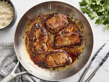 Overhead view of glazed pork chops in a skillet.