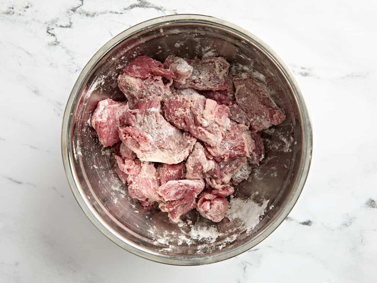 Beef stew meat in a bowl covered in flour.