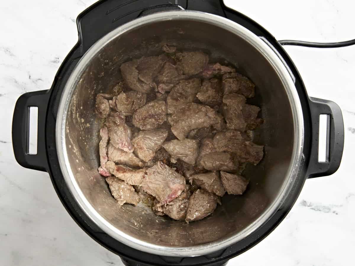 Browned beef stew meat in an Instant Pot.