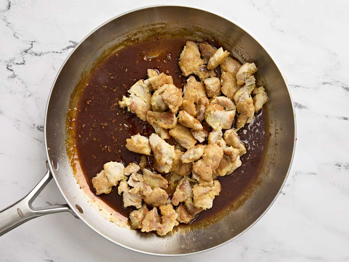 Cooked chicken added to the orange sauce in a skillet.