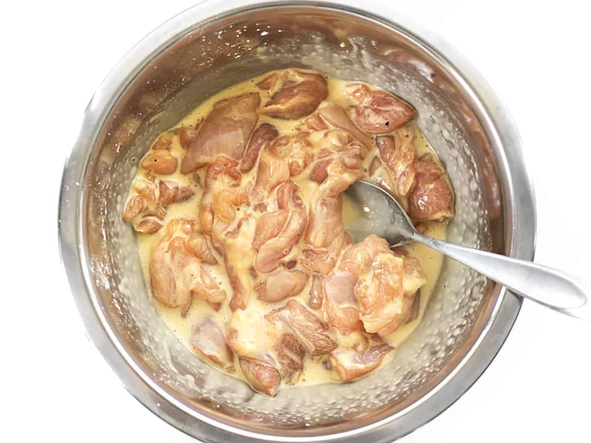 Chicken pieces in the bowl coated with the cornstarch and egg batter.