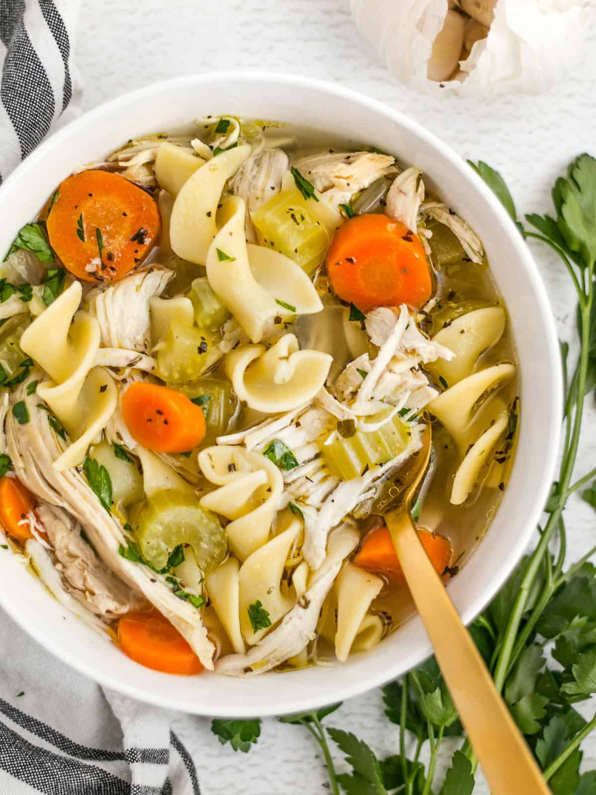 Close up overhead view of a bowl of homemade chicken noodle soup with a gold spoon.