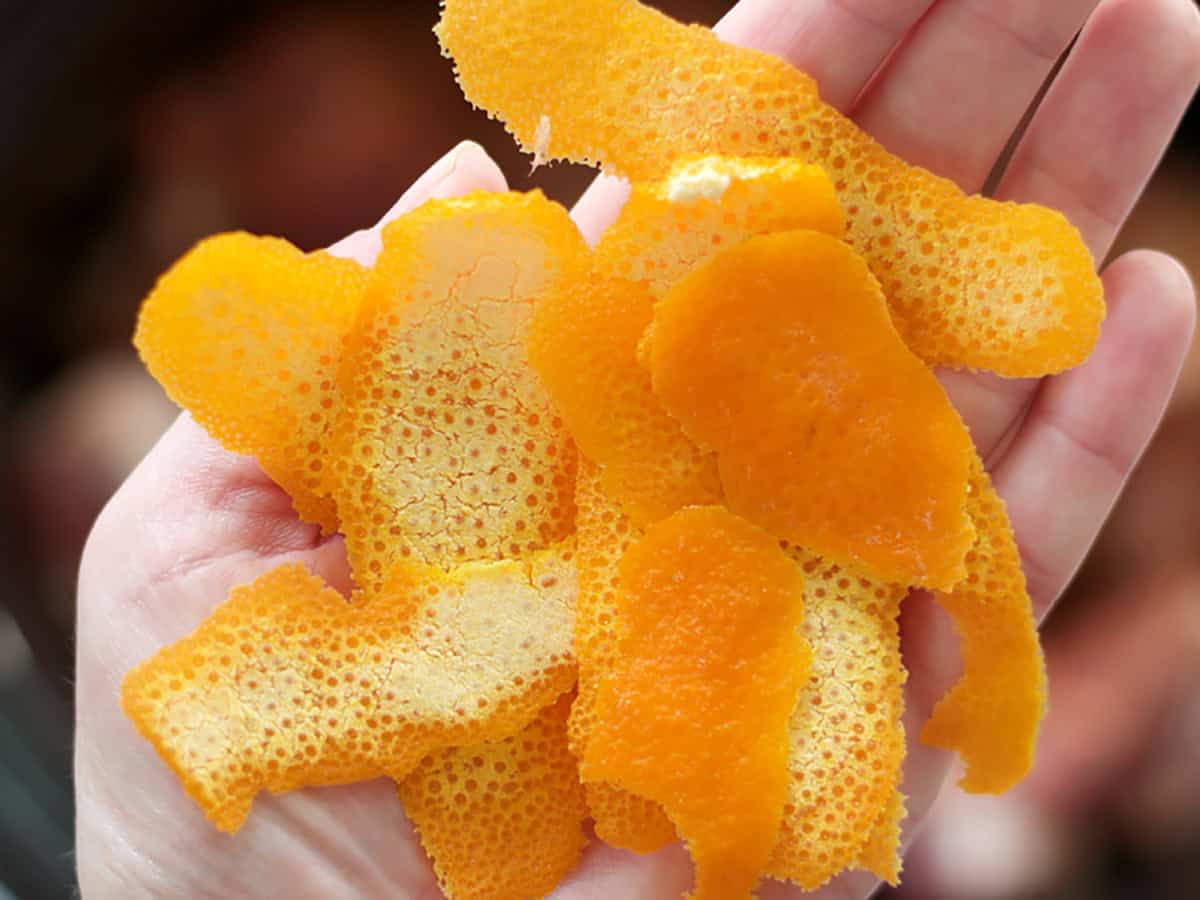 Orange peels held in the palm of a hand.