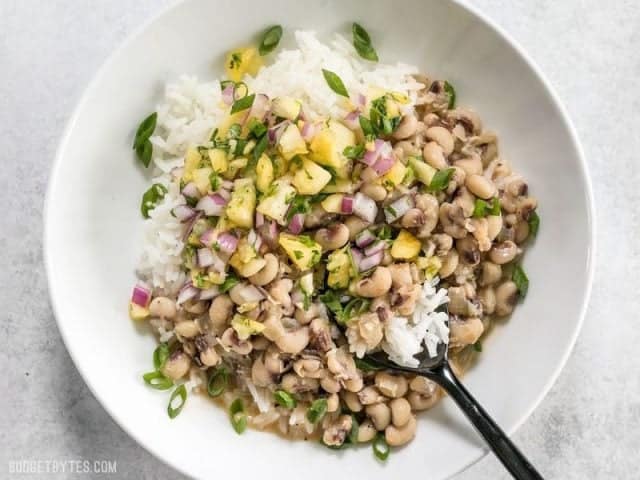 These rich and spicy Coconut Jerk Peas are super simple to make and pair brilliantly with a sweet and vibrant pineapple salsa. BudgetBytes.com