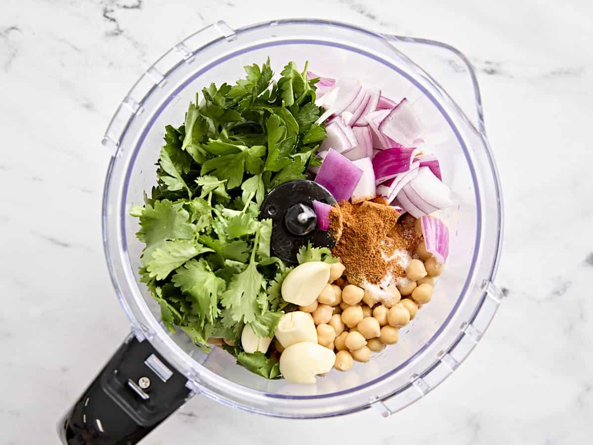 Chickpeas, parsley, cilantro, diced red onion, garlic cloves, cumin, cayenne, and salt in a food processor.