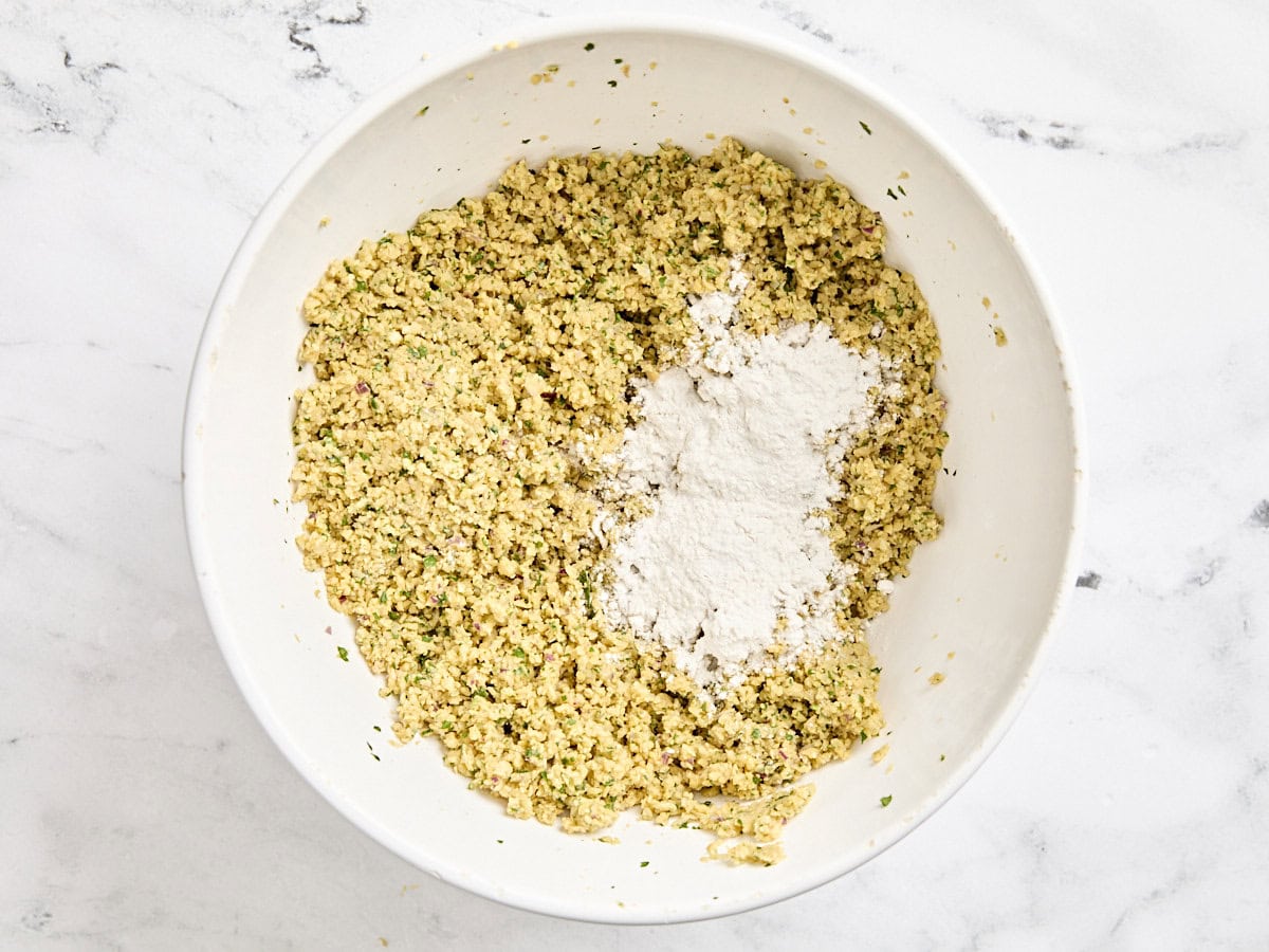 Falafel mix in a mixing bowl with flour added.