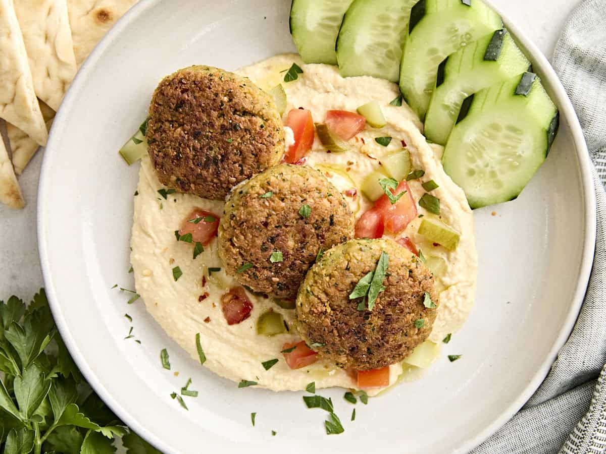 Homemade falafel on top of some hummus with salad.