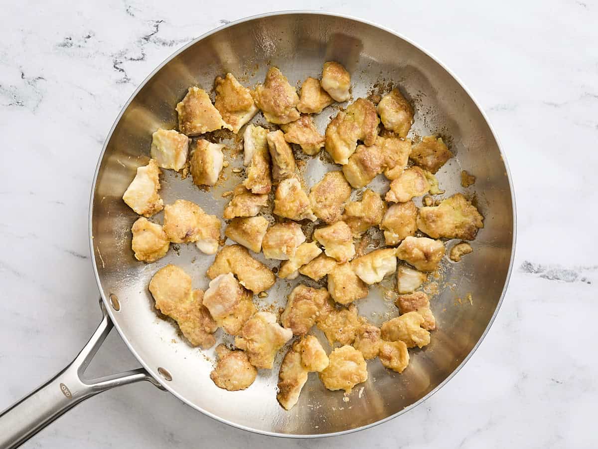 Browned chicken thigh pieces in a skillet.