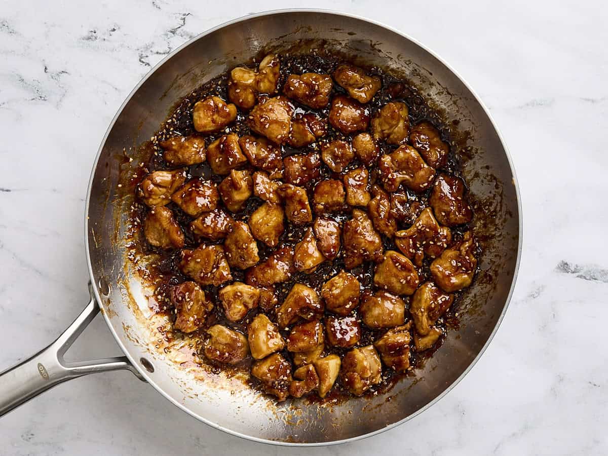 The sesame and soy sauce mix added to the cooked chicken thigh pieces in a skillet to make sesame chicken.