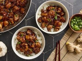 Overhead view of sesame chicken in bowls with rice.