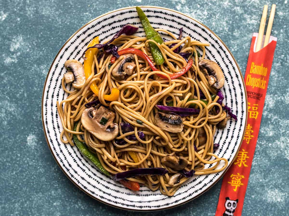 Overhead view of lo mein on a plate with chopsticks on the side.