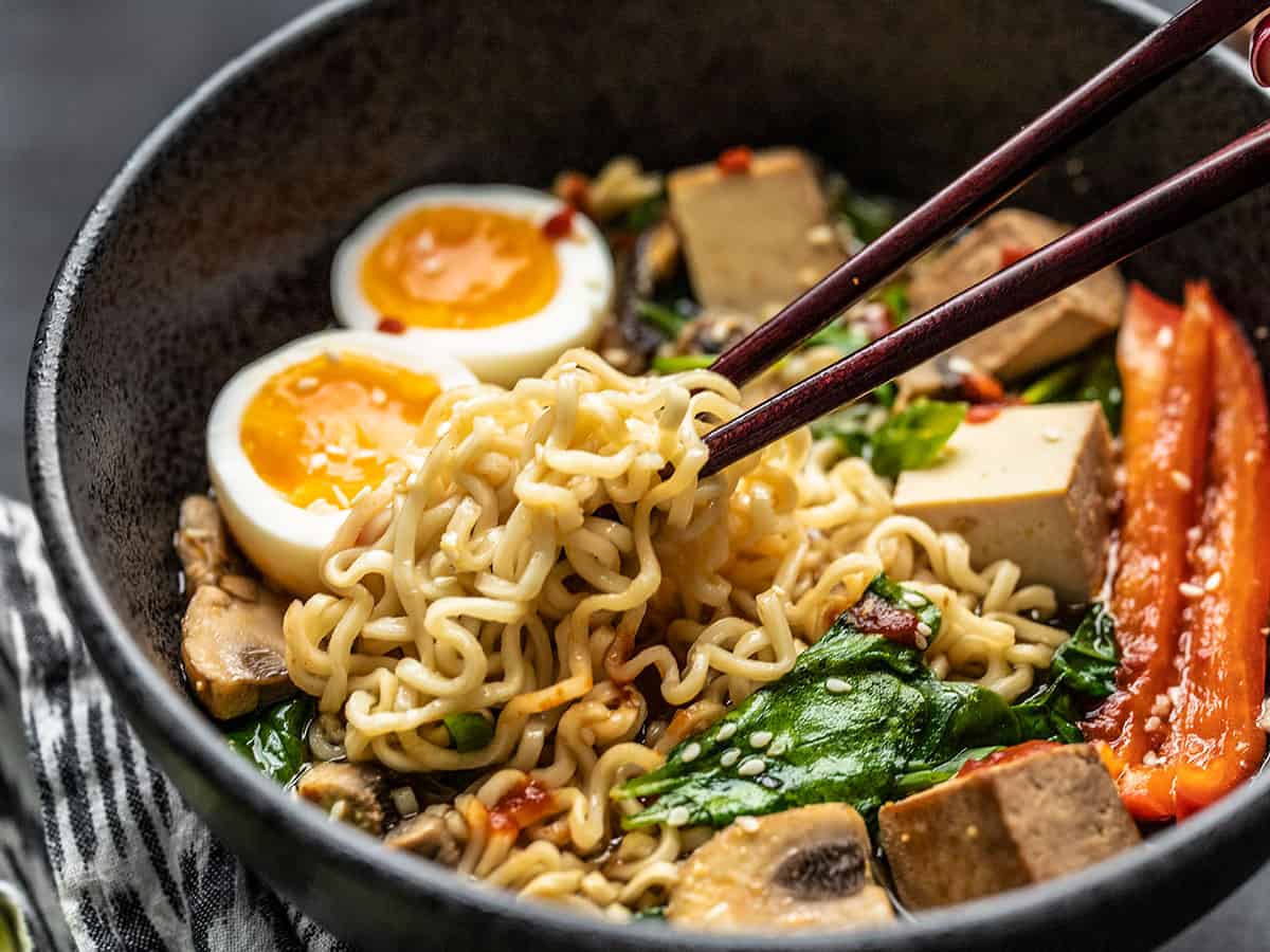 Close up side view of ramen noodles being picked up out of the bowl by chopsticks.