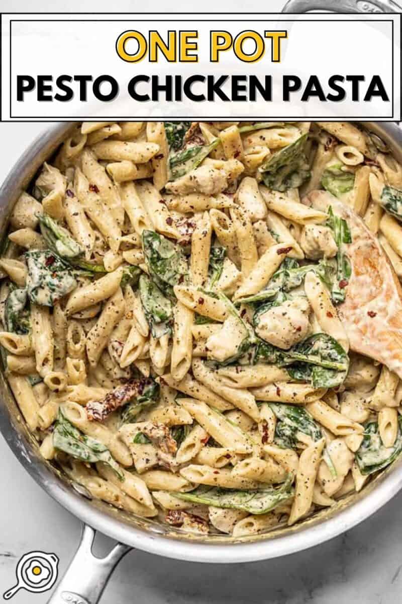 close up of creamy pesto chicken pasta in a skillet with a wooden spoon