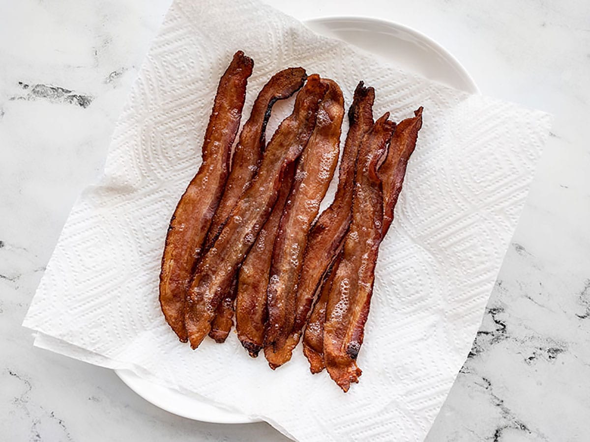 Baked bacon draining on a paper towel lined plate. 