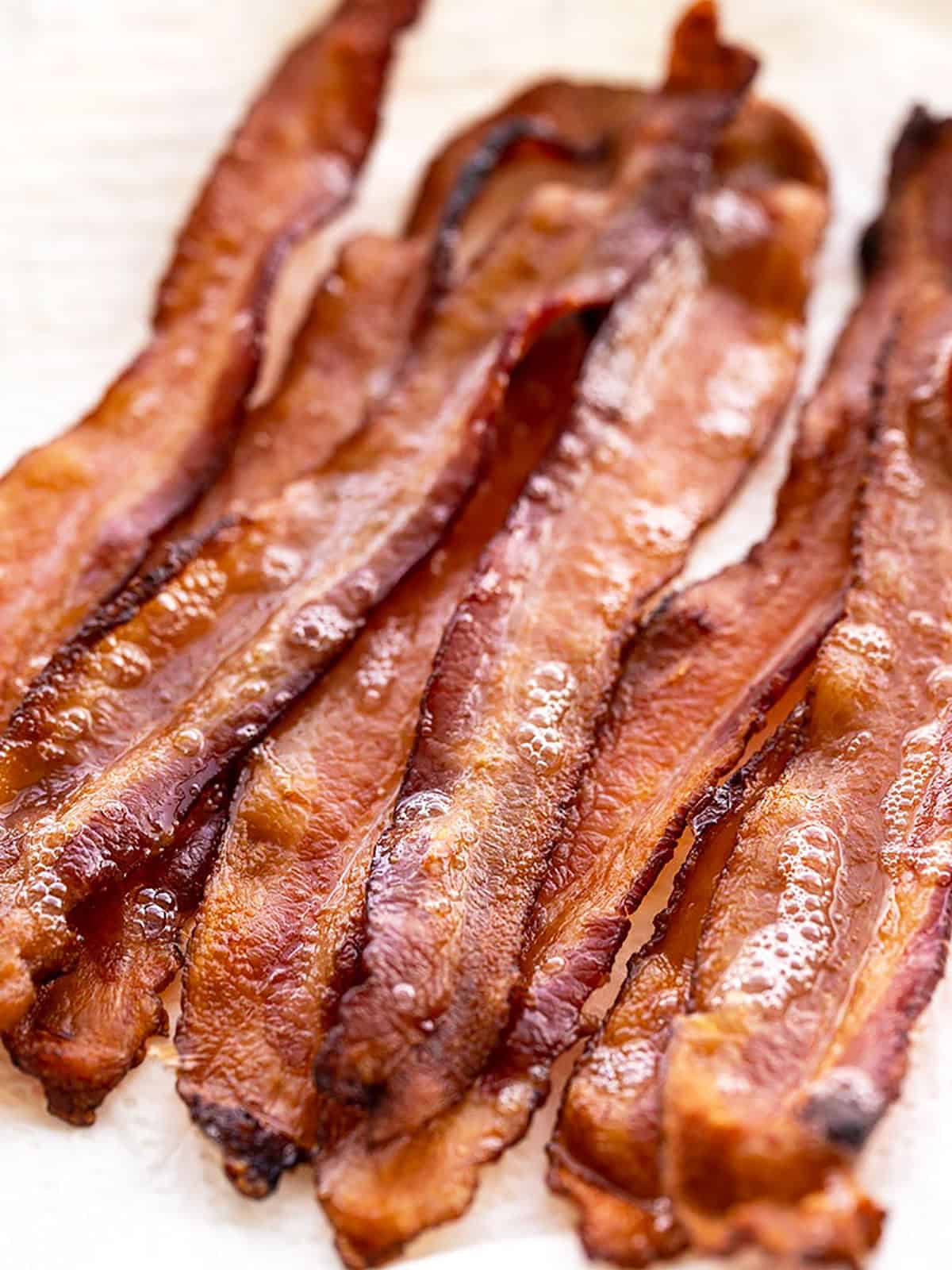 Close up view of oven baked bacon strips on a paper towel lined plate.