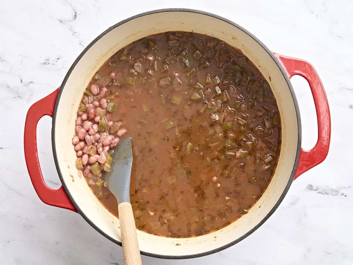 Red beans and veggies in a pot with a spoon after simmering.