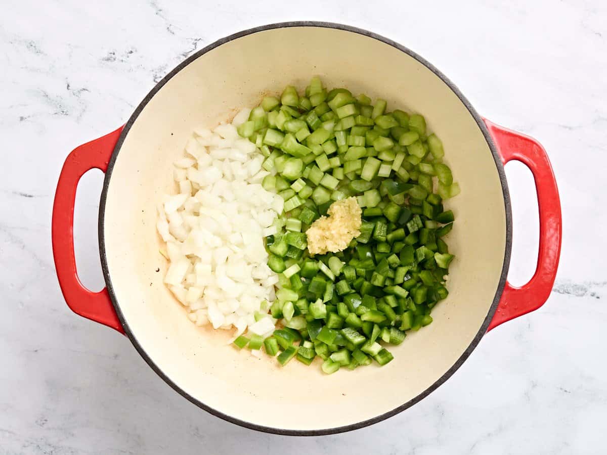 Diced onion, green bell pepper, celery, and minced garlic in a pot.