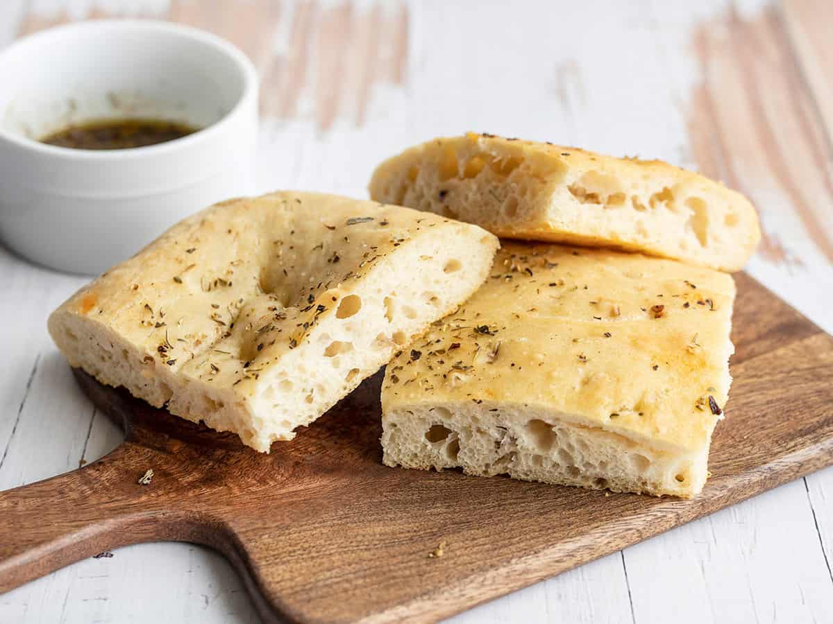 Slices of focaccia bread on a wooden cutting board.