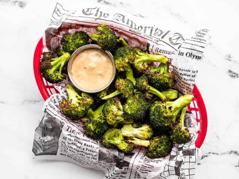 Overhead view of a basket full of oven roasted broccoli with dipping sauce