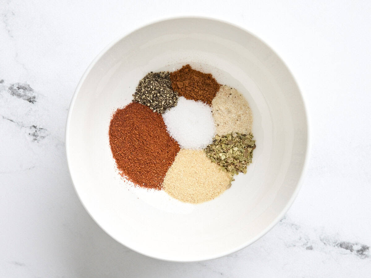 A bowl of seasonings for baked chicken drumsticks.