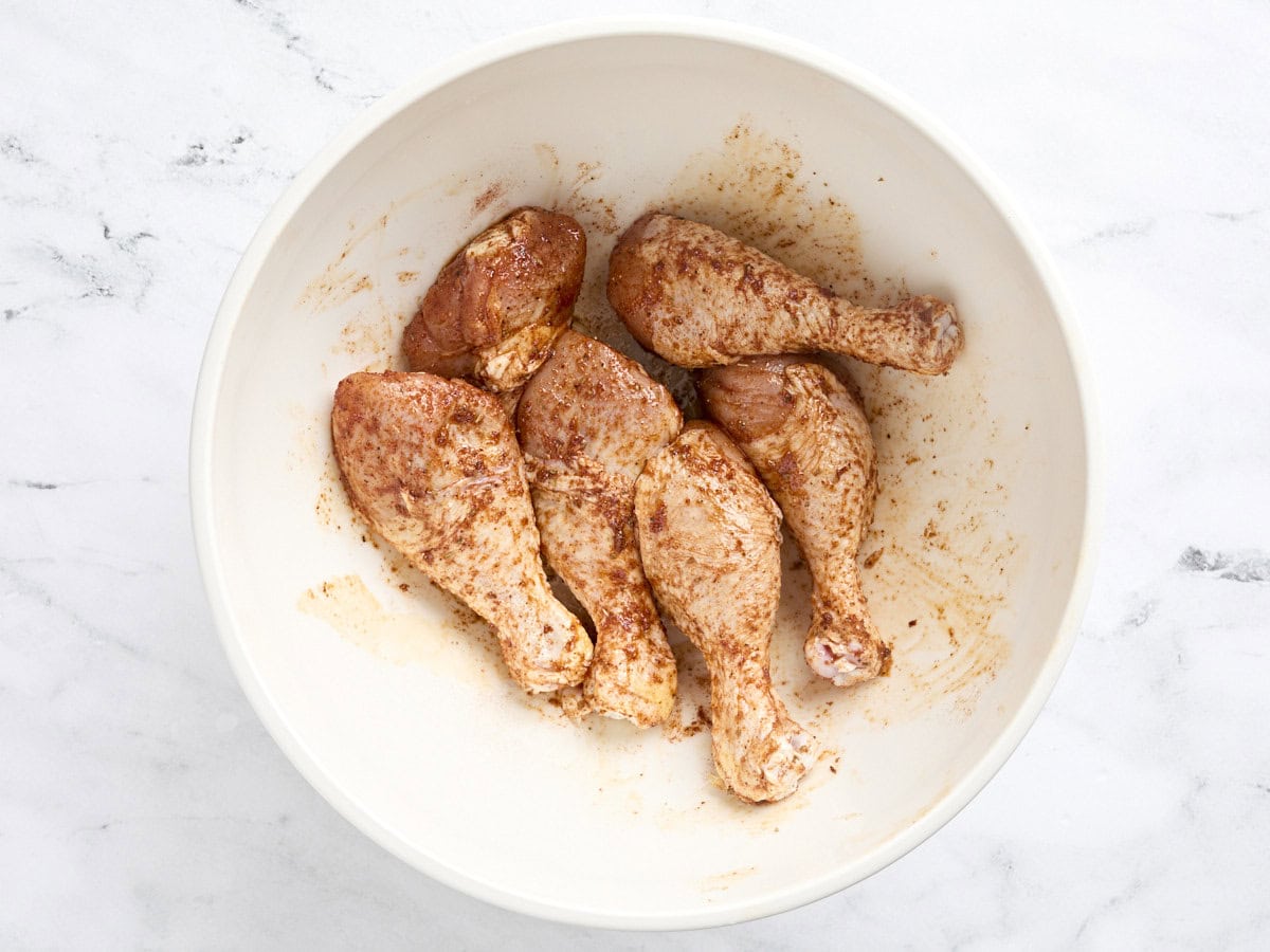 Seasoned chicken drumsticks in a bowl.