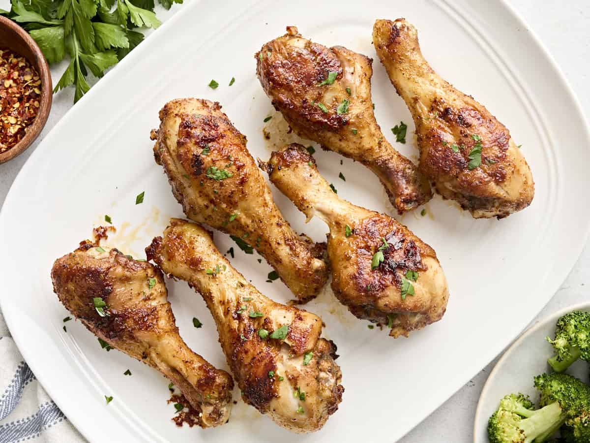 Overhead view of baked chicken drumsticks on a serving platter.