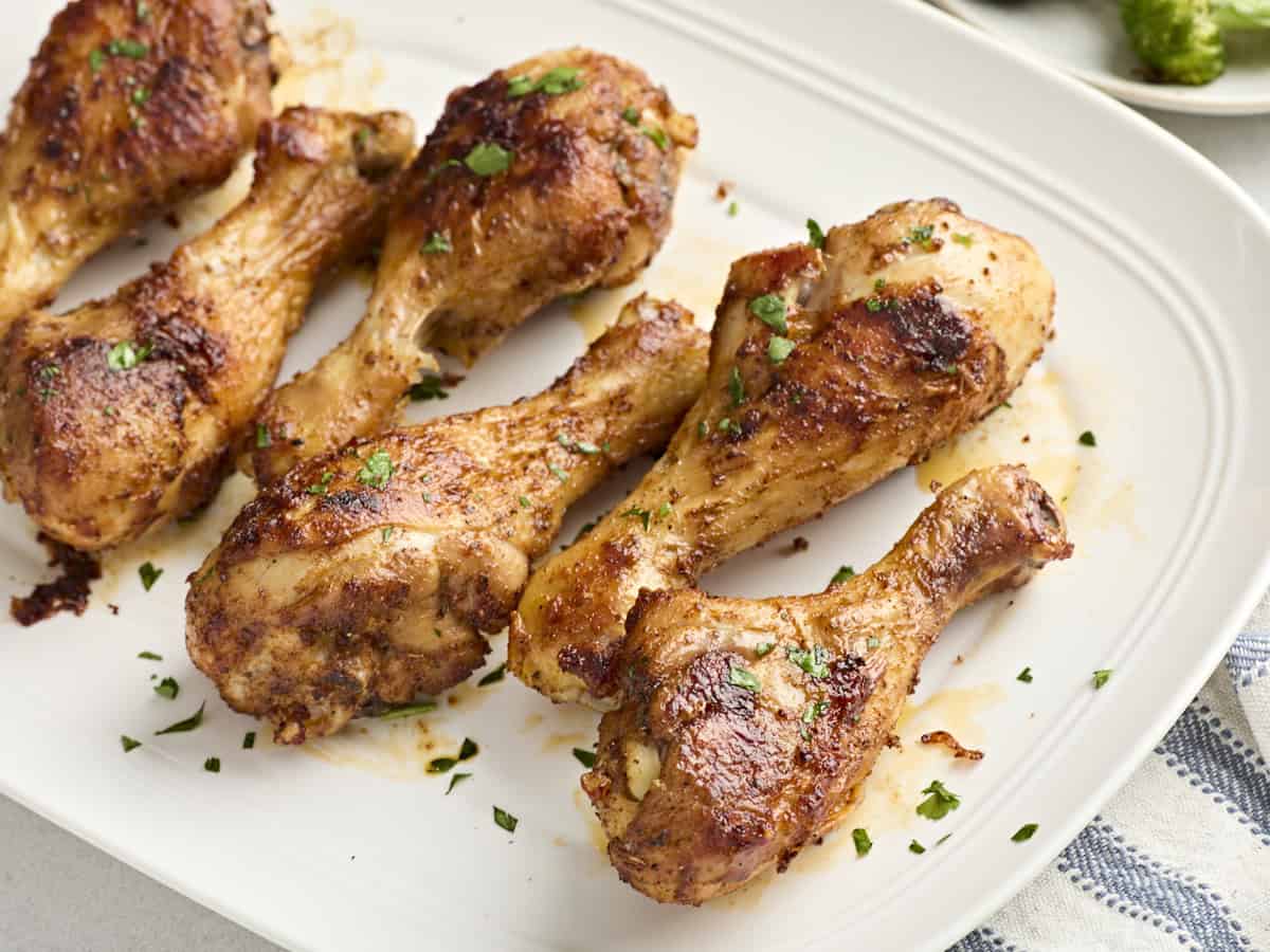 Close up of baked chicken drumsticks on a plate.