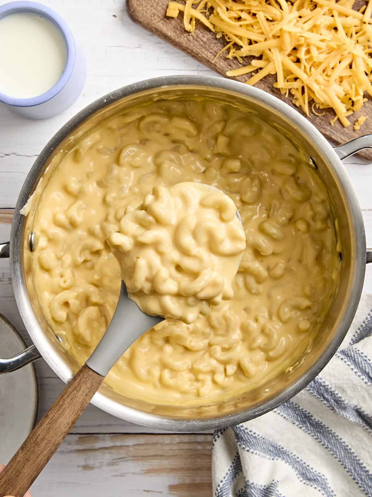 Overhead view of mac and cheese in a sauce pan, with some on a serving spoon.