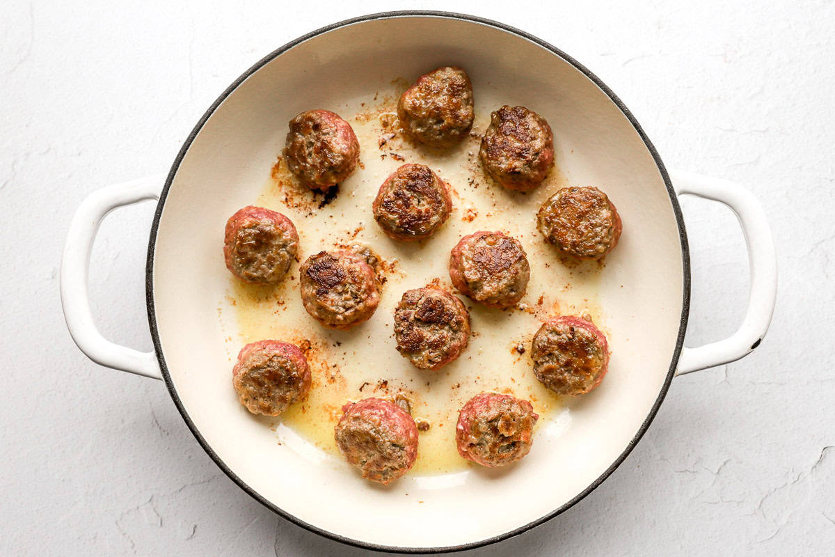 Meatballs cooking in a skillet.