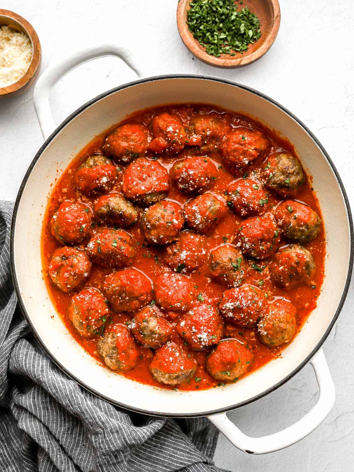 Overhead view of homemade meatballs cooking in a red sauce in a skillet.