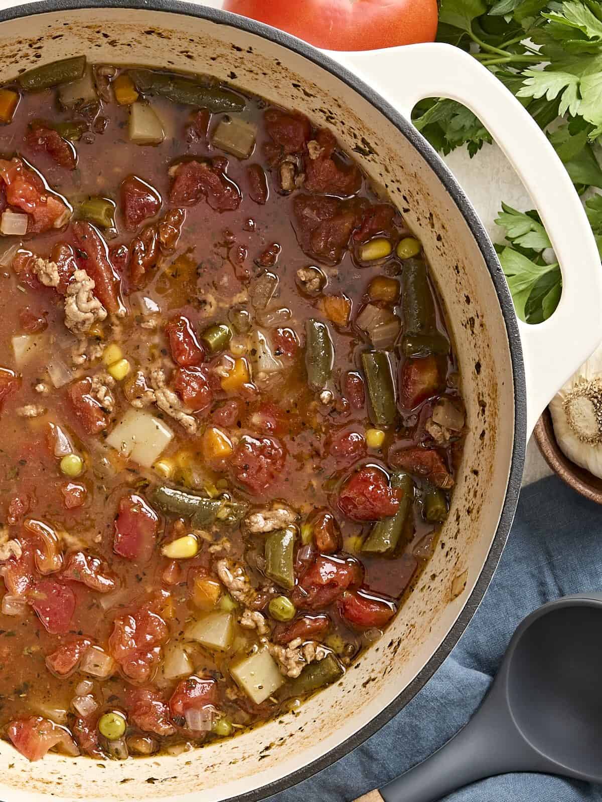 Overhead view of vegetable beef soup in a soup pot.