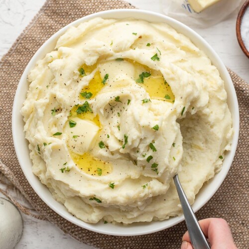 Mashed potatoes being scooped out of a bowl.