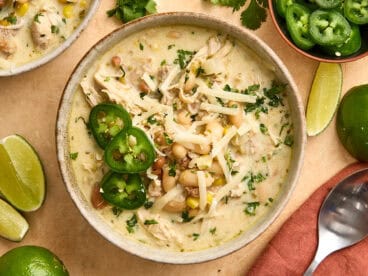 Overhead view of white chili chicken in a bowl, topped with shredded cheese and sliced jalapenos.