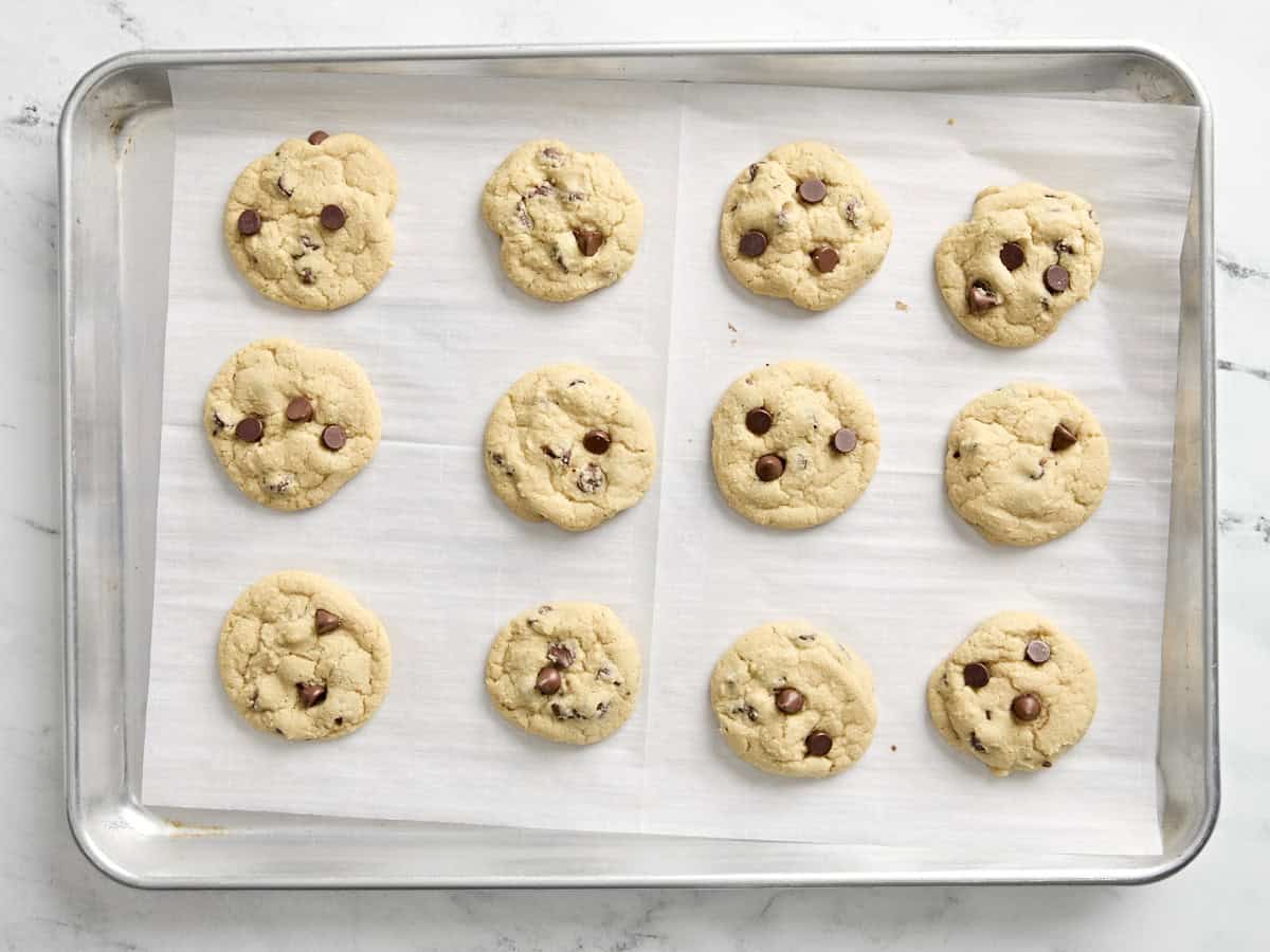 Chocolate chip cookies on a parchment lined baking sheet.