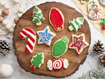 Overhead view of festive sugar cookies on a wooden board.