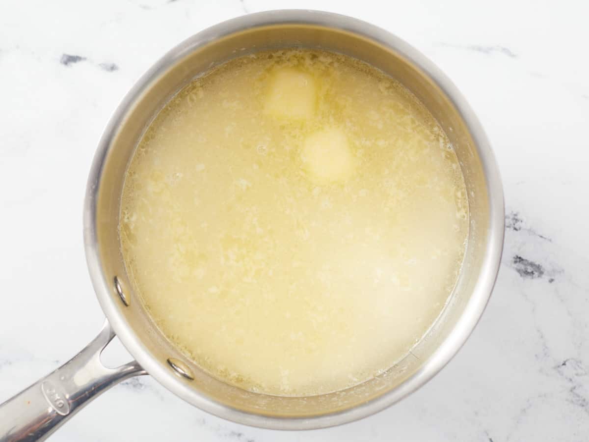 Overhead shot of butter, water, and rice in a pot.